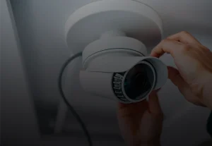A person installing a security camera on the ceiling.
