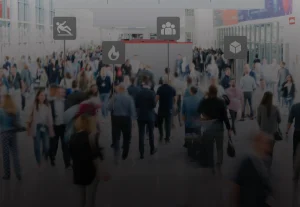 Crowd of people in a busy location with safety signs and direction indicators.