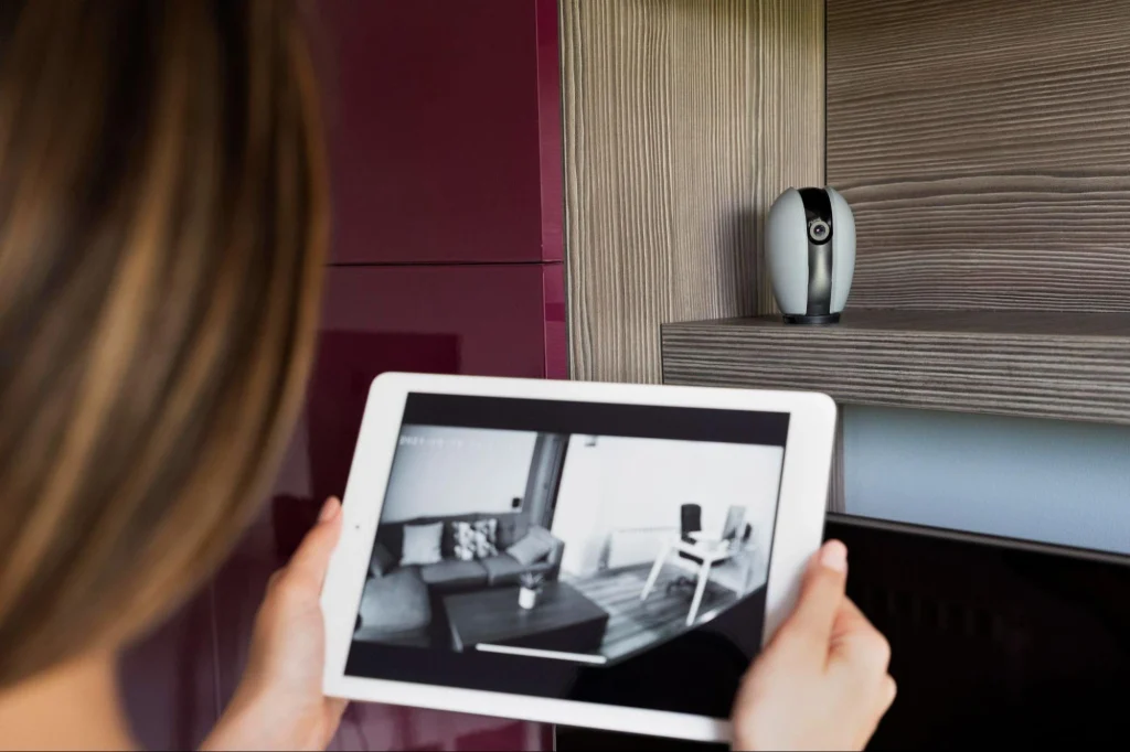 Une femme surveille les images d'une caméra dôme d'intérieur sur une tablette pour assurer la sécurité de sa maison.