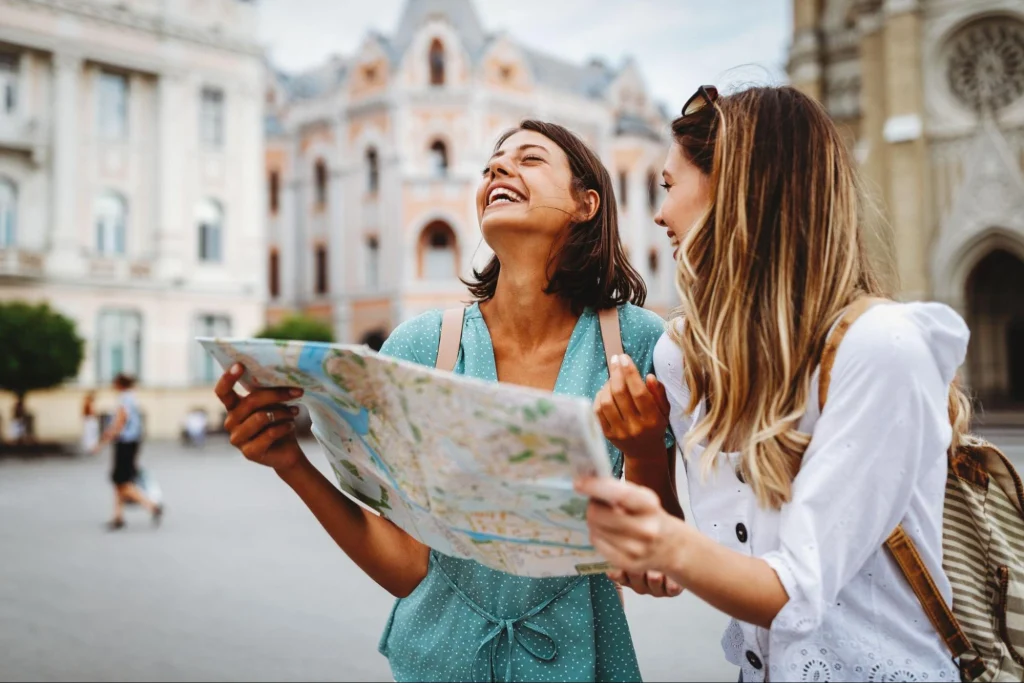 Two happy women tourists with map exploring city, symbolizing safe travel and tourism in El Paso 2025