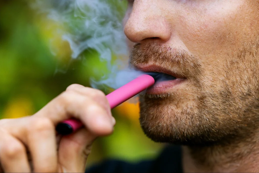 Homme utilisant un dispositif de vaporisation rose produisant de la vapeur par rapport à la fumée détectée par les alarmes ordinaires