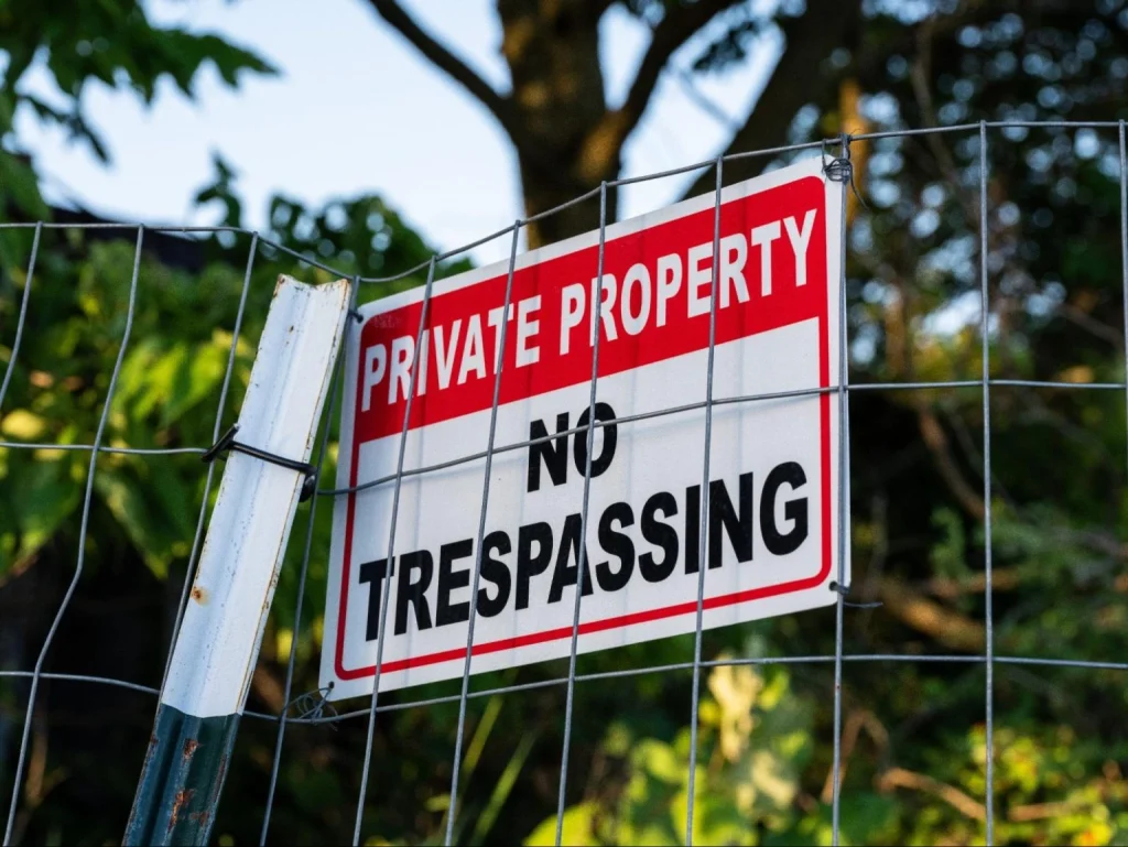 Panneau d'interdiction d'accès à une propriété privée sur une clôture métallique mettant en garde contre toute entrée ou intrusion illégale.