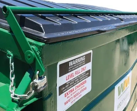 Locked dumpster with warning label and safety regulations.