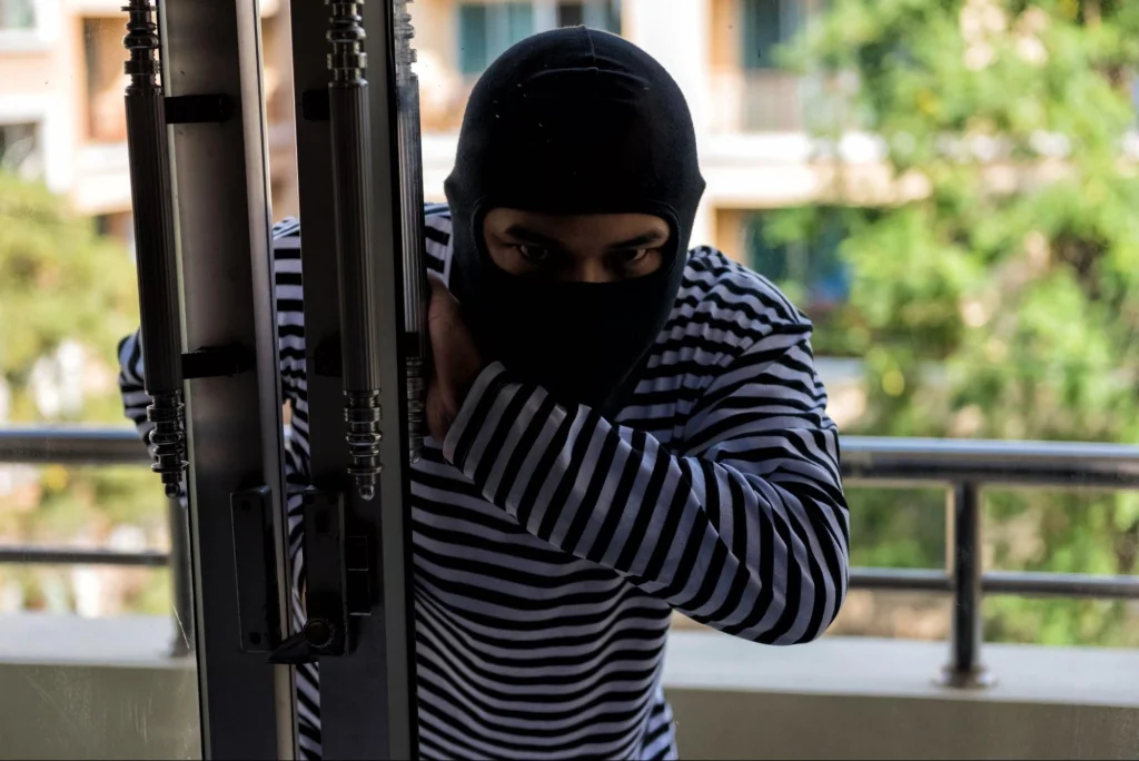 Intruder attempting to break into a building, wearing a balaclava.
