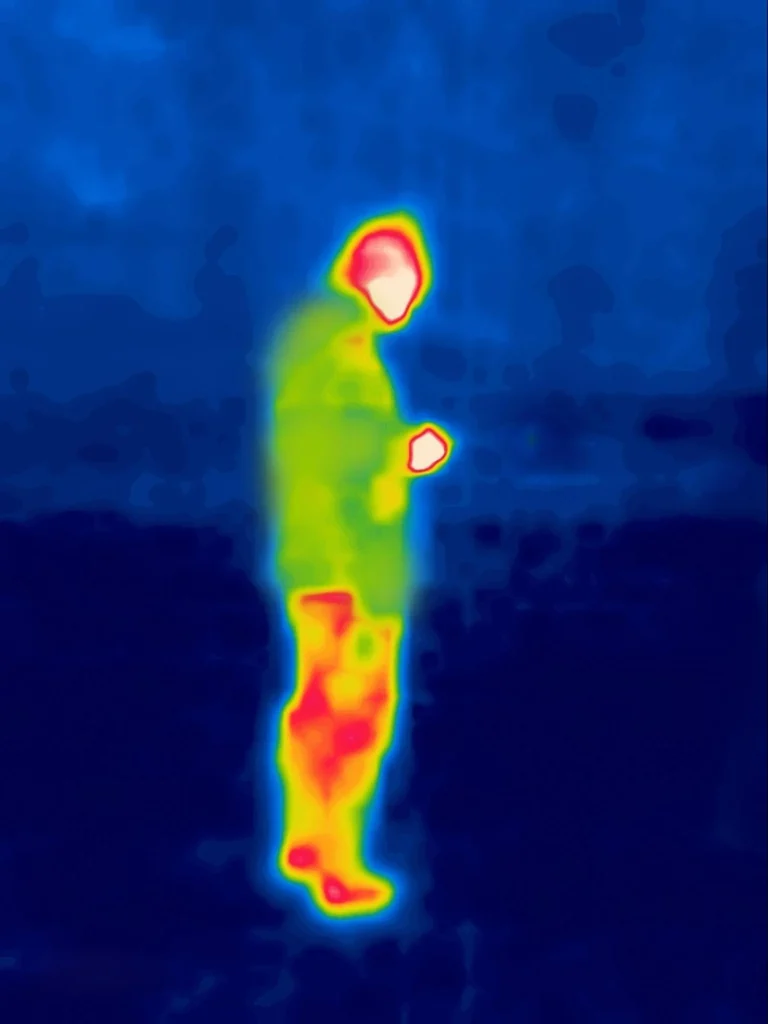 Image thermique d'une personne marchant dans un parking la nuit.