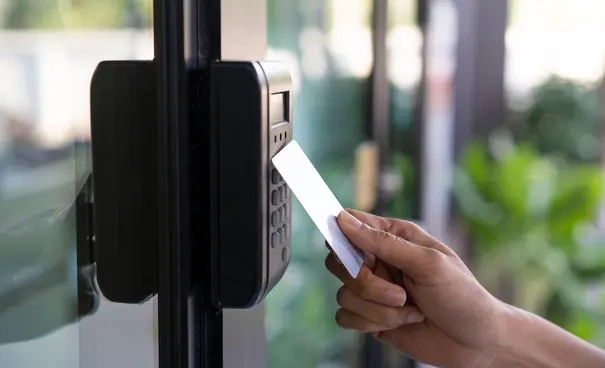 Person using an RFID card on an access control keypad to open a door.